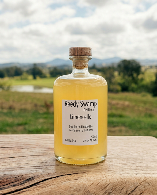 Bottle of Reedy Swamp Distillery Limoncello on a wooden surface with a Bega valley scenic background