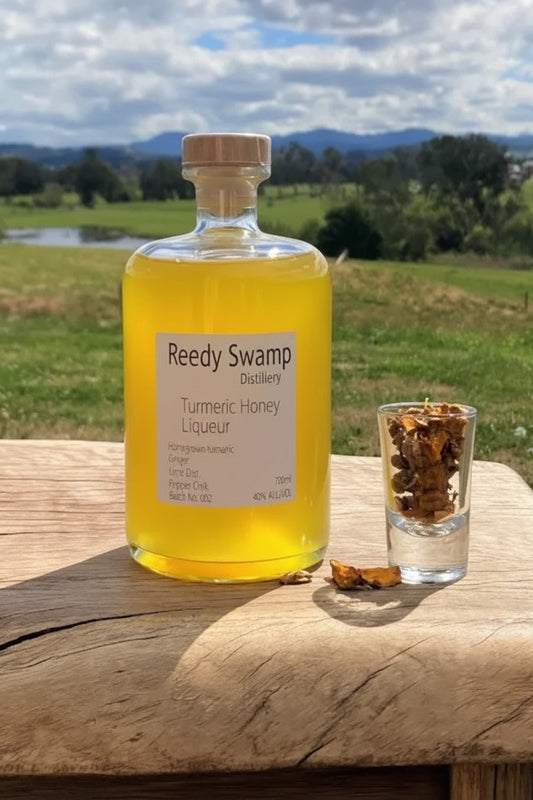 Bottle of Reedy Swamp Turmeric Honey Liqueur on a wooden surface with a scenic background