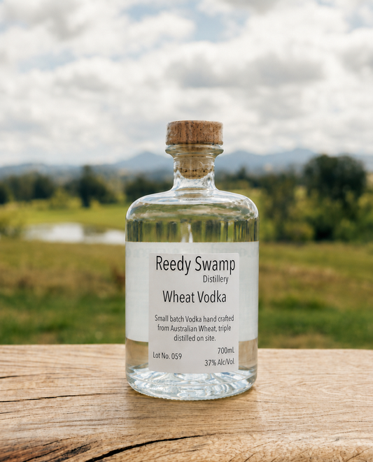 Bottle of Reedy Swamp Smal batch Wheat Vodka on a timber bench set in the scenic Bega Valley background